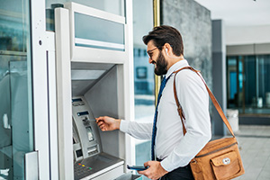 Person smiling using a bank machine that works due to ITM service